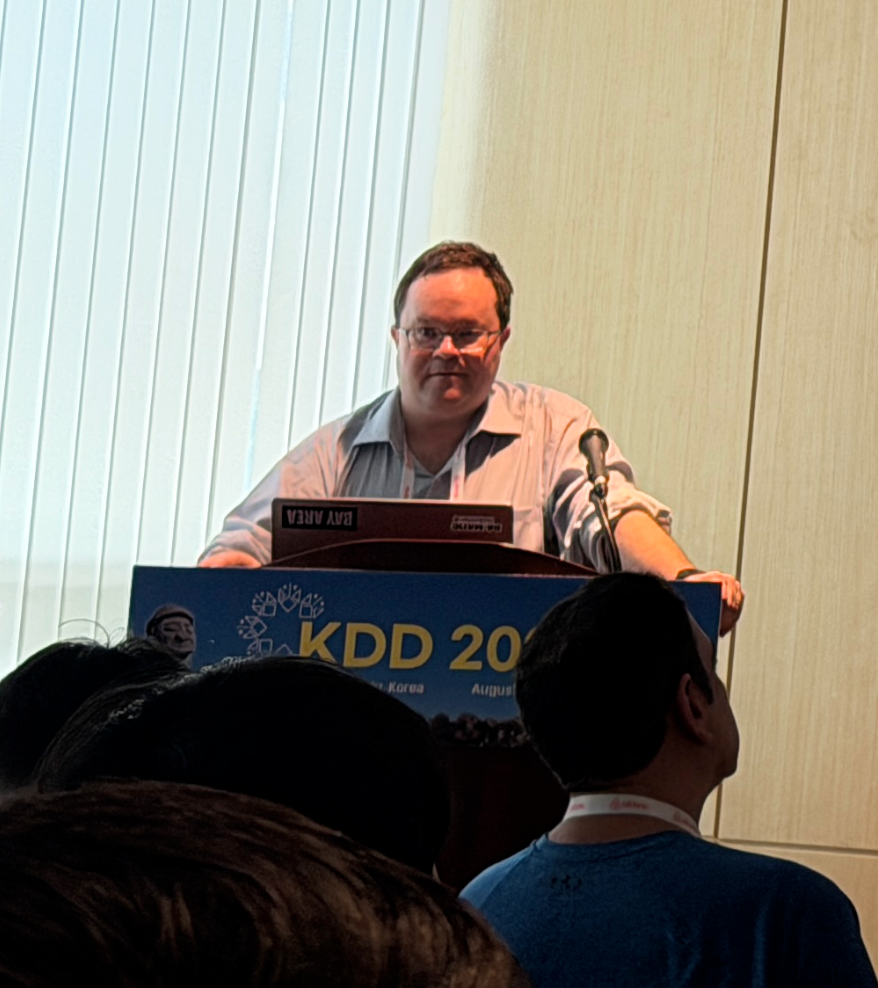 David Purdy presenting at a KDD conference, with attendees in the foreground.